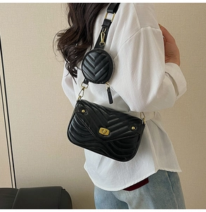 Detail of black quilted crossbody bag with wide strap and detachable round coin purse