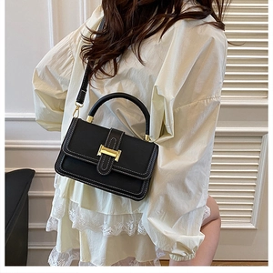 Close-up of black leather handbag with white contrast stitching and gold H-clasp