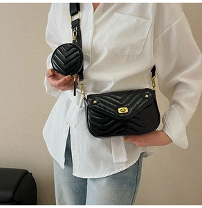 Close-up of black quilted crossbody bag with small round coin pouch on wide strap