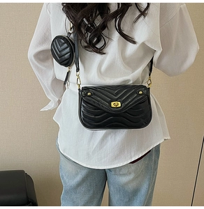 Detail of a black quilted crossbody bag with a round coin purse and wide shoulder strap