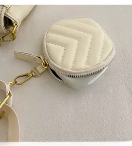 Close-up of a beige round coin purse with V-quilted texture and gold metal clasp