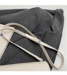 Detail of adjustable shoulder strap with silver metal buckle on white faux leather bag
