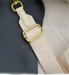 Detail view of the adjustable beige fabric strap with polished gold-tone metal buckle