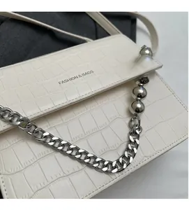 Detail of off-white crocodile pattern bag with silver chain and pearl decoration