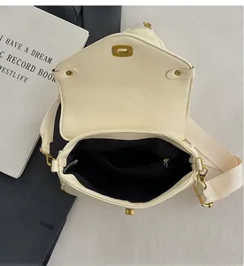 Detail view of the spacious inner compartment with zip pocket of the ivory crossbody bag