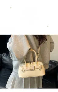 Detail of beige shell handbag showing silver metal buckle and adjustable shoulder strap