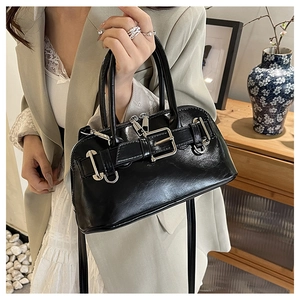 Detailed shot of a black glossy shell bag featuring a silver buckle and dual zippers