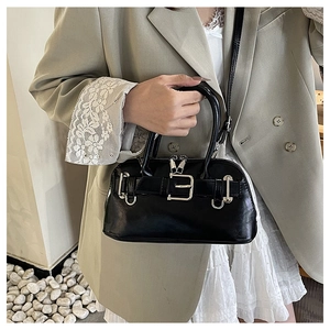 Close-up of black shell handbag featuring metallic buckle and adjustable shoulder strap