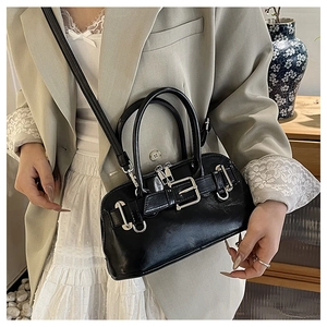 Close-up of black glossy shell bag with silver buckle and adjustable shoulder strap