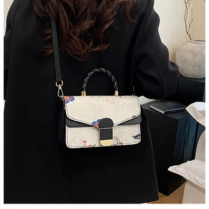 Umhängetasche mit Blumenprint und Schmetterlingen an einem Model in minimalistischer Szene