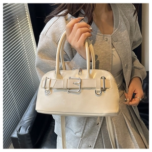 Detail of cream white shell bag showing sleek faux leather texture and metal buckle strap