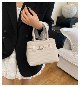 Detail of beige woven tote bag featuring a silver metal buckle and elegant PU leather trim