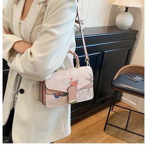 Detail der rosa Handtasche mit floralem Muster, Goldschließe und blauen Schmetterlingen