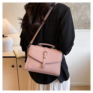 Detail of pink pebbled leather crossbody bag showing metal buckle and shoulder strap
