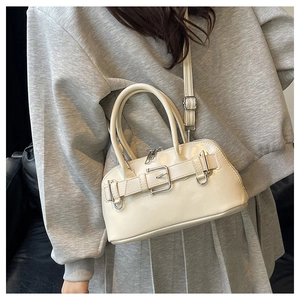 Detail of a creamy white shell bag with adjustable strap and silver buckle accent