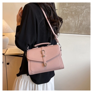 Chic pink textured leather messenger bag with silver metallic buckle on a lifestyle setting