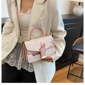 Detail der rosa Blumentasche mit geflochtenem Griff an einem Model im weißen Blazer