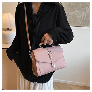 Detail view of pink pebbled leather handbag with silver buckle and adjustable strap