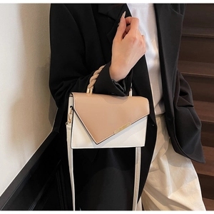 Close-up of contrast-colored handbag with geometric flap and gold metal hardware