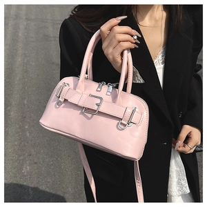 Pink shell handbag detail featuring decorative leather strap and silver metal buckle