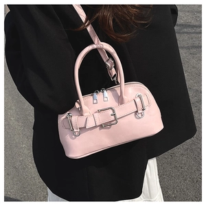 Pink shell handbag styled as crossbody with decorative belt buckle on casual outfit