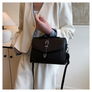 Close-up of black lychee-grain leather texture and silver buckle on shoulder bag