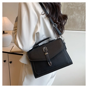 Close-up of black lychee grain leather texture with silver buckle and flap on the bag