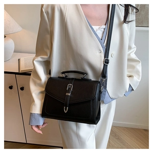 Detail of black pebbled leather handbag with silver buckle and adjustable shoulder strap