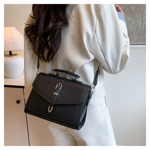 Detail of black pebbled leather texture on minimalist shoulder bag with silver buckle