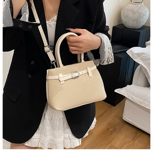Detail of beige woven tote bag with cream leather handles and strap on elegant model