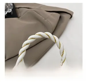 Detail des geflochtenen weißen Ledergriffs mit Goldakzenten an der floralen Tasche