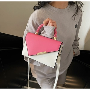 Detail of a pink and white color-block handbag with twist-rope handle and gold metal clasp