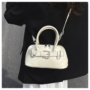 Close-up of beige shell bag featuring stylish belt buckle detail and silver hardware