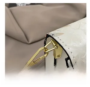 Detail des Blumendrucks auf weißer Handtasche mit goldenem Metallhaken und feiner Naht