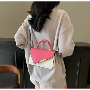Detail view of pink and white color-block handbag showing texture and metal bar buckle