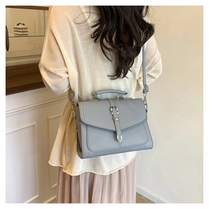 Detail view of grey leather shoulder bag styled on a model in a minimal interior