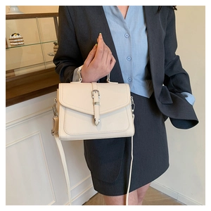 Detail of cream white leather handbag with lychee texture and metallic buckle strap
