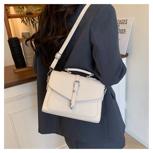 Detailed view of cream white crossbody bag with lychee texture and buckle strap