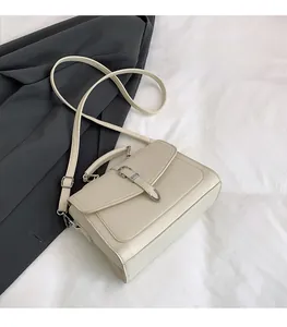 Close-up of textured leather crossbody bag with silver rotating lock and top handle