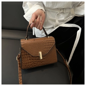 Détail d'un sac à main marron à motif crocodile avec fermoir doré et texture vintage