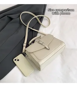 Size comparison of cream textured crossbody bag next to a smartphone showing scale