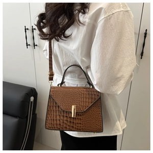 Détail d'un sac marron texture crocodile avec fermoir métallique doré et bandoulière