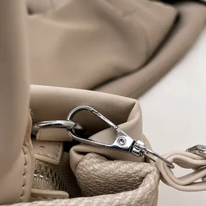 Close-up of premium silver metal hook and leather strap connection on beige tote bag