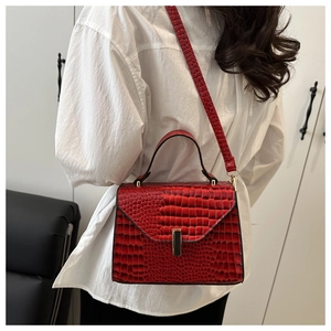 Détail d'un sac rouge foncé à motif crocodile avec boucle dorée et bandoulière ajustable