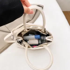 Detail view of the interior capacity of this cream handbag showing cosmetic storage