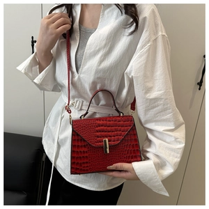 Gros plan détaillé d'un sac à main rouge texture crocodile avec fermoir en métal doré