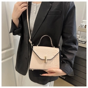 Détail du sac rose embossé crocodile avec boucle dorée sur un blazer noir chic