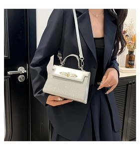 Detail of silver glitter handbag featuring gold metal bar lock and textured hard PU surface