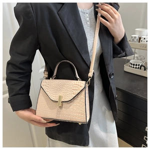 Détail du petit sac rose poudré à motif crocodile et boucle dorée sur blazer noir