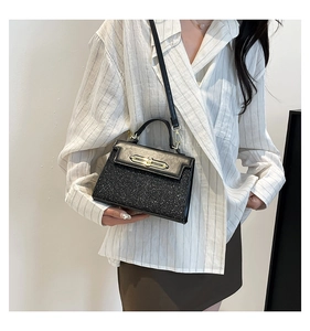 Detail of black glitter mini handbag with golden clasp and detachable strap on model